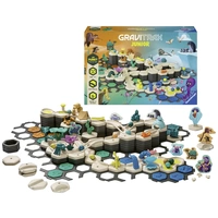 Ein GraviTrax Junior Spielset mit verschiedenen Bahnelementen und Figuren. Im Hintergrund sieht man die farbenfrohe Verpackung.
